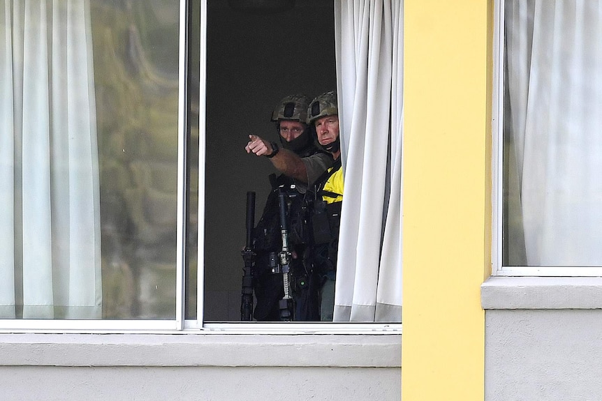 Emergency response police officers pointing out through an apartment window