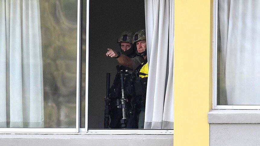 Emergency response police officers pointing out through an apartment window