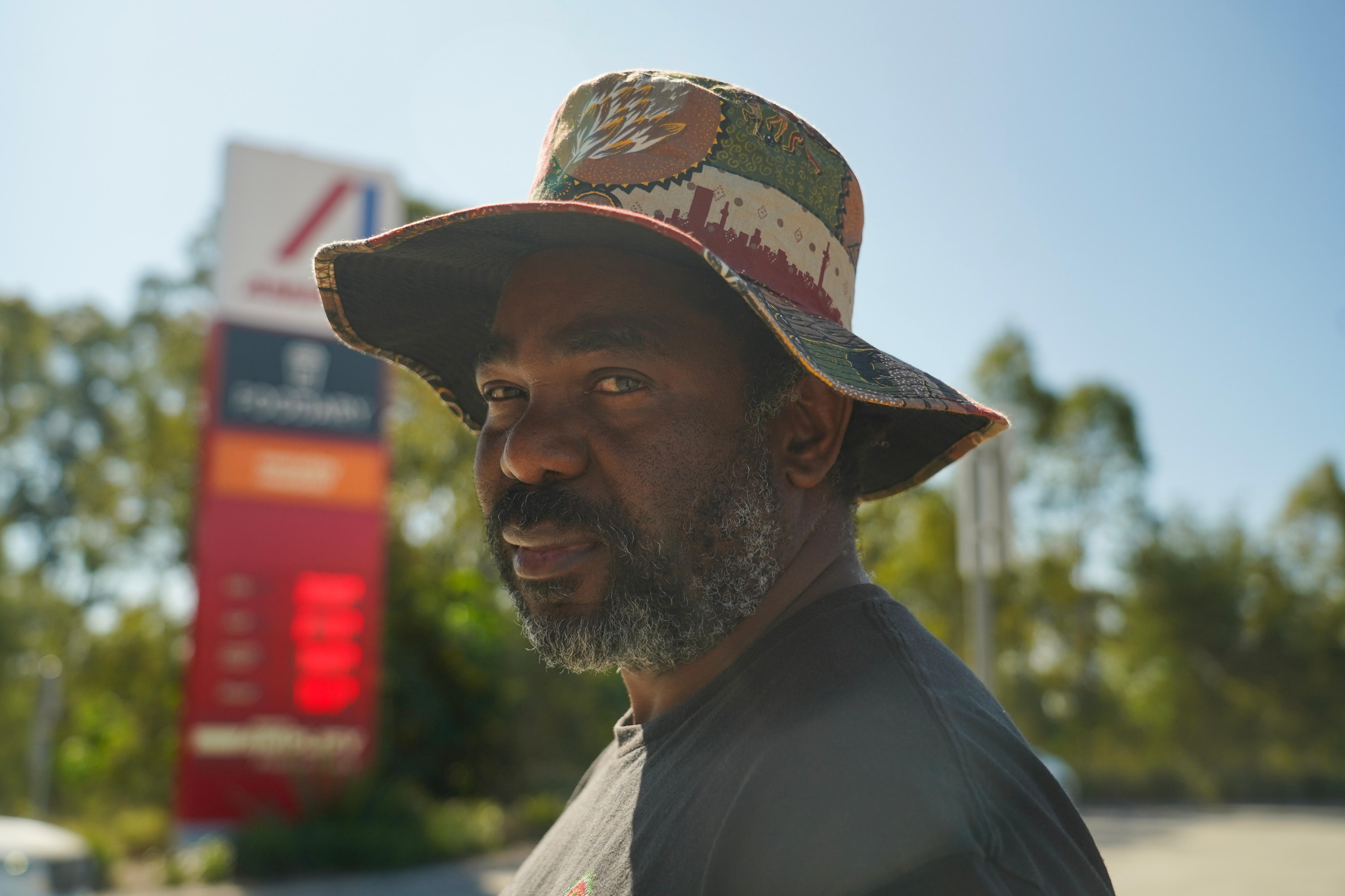 Black man with hat standing in front of petrol station