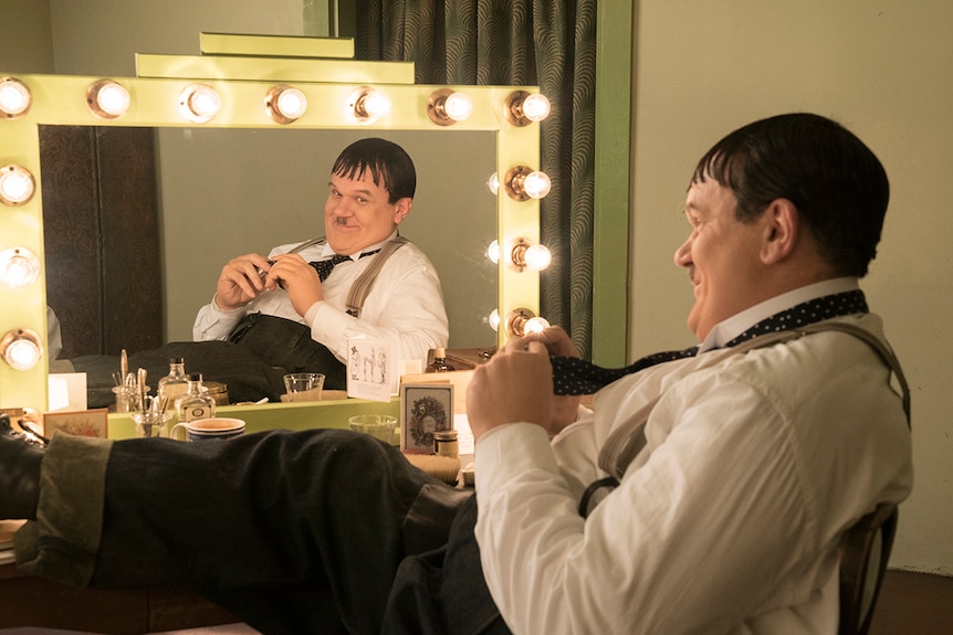 Colour still of John C. Reilly looking in dressing room mirror in 2018 film Stan and Ollie.