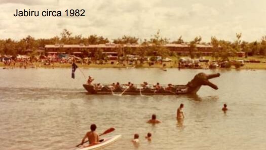 An old photograph of residents swimming, kayaking and riding a crocodile-themed boat in the Jabiru lake.