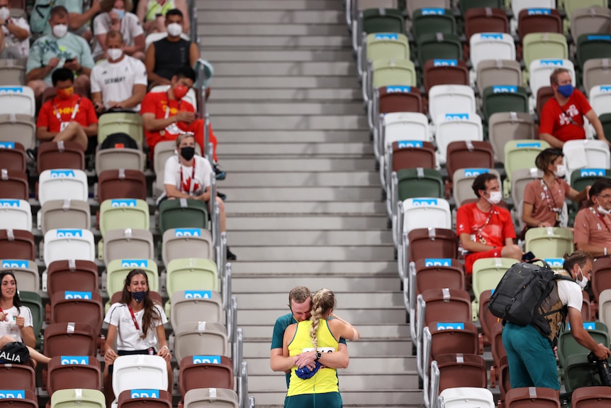 Kelsey-Lee Barber hugs her husband and coach in front of near-empty stands after winning javelin bronze at the Tokyo Olympics.