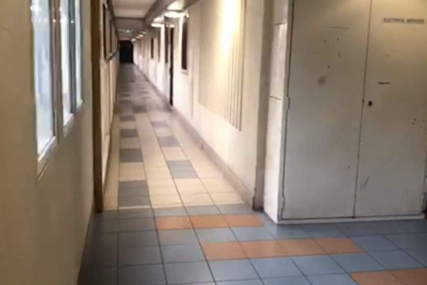 A still from a video of a thin, tiled hallway in an apartment complex.