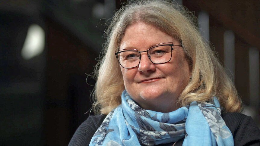 Linda Peach wears a blue scarf and glasses.