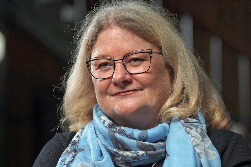 Linda Peach wears a blue scarf and glasses.