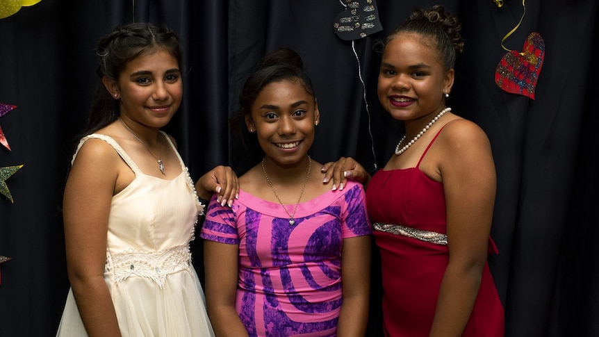 Three young girls stand side by side in their dresses for the Naidoc Ball