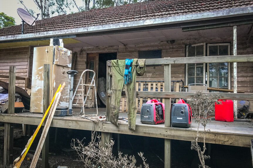 A flooded house with items outside including pumps and overalls.