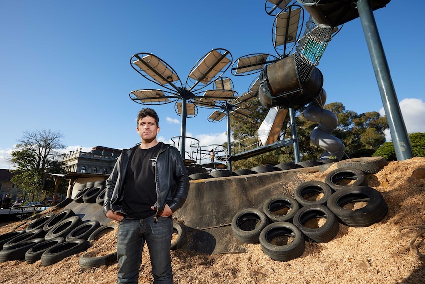 Benjamin Gilbert stands in front of a playground designed to look like flowers