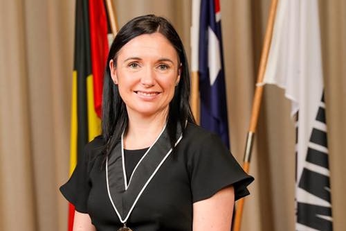 Carly Moore, a woman with dark hair, smiles at the camera.