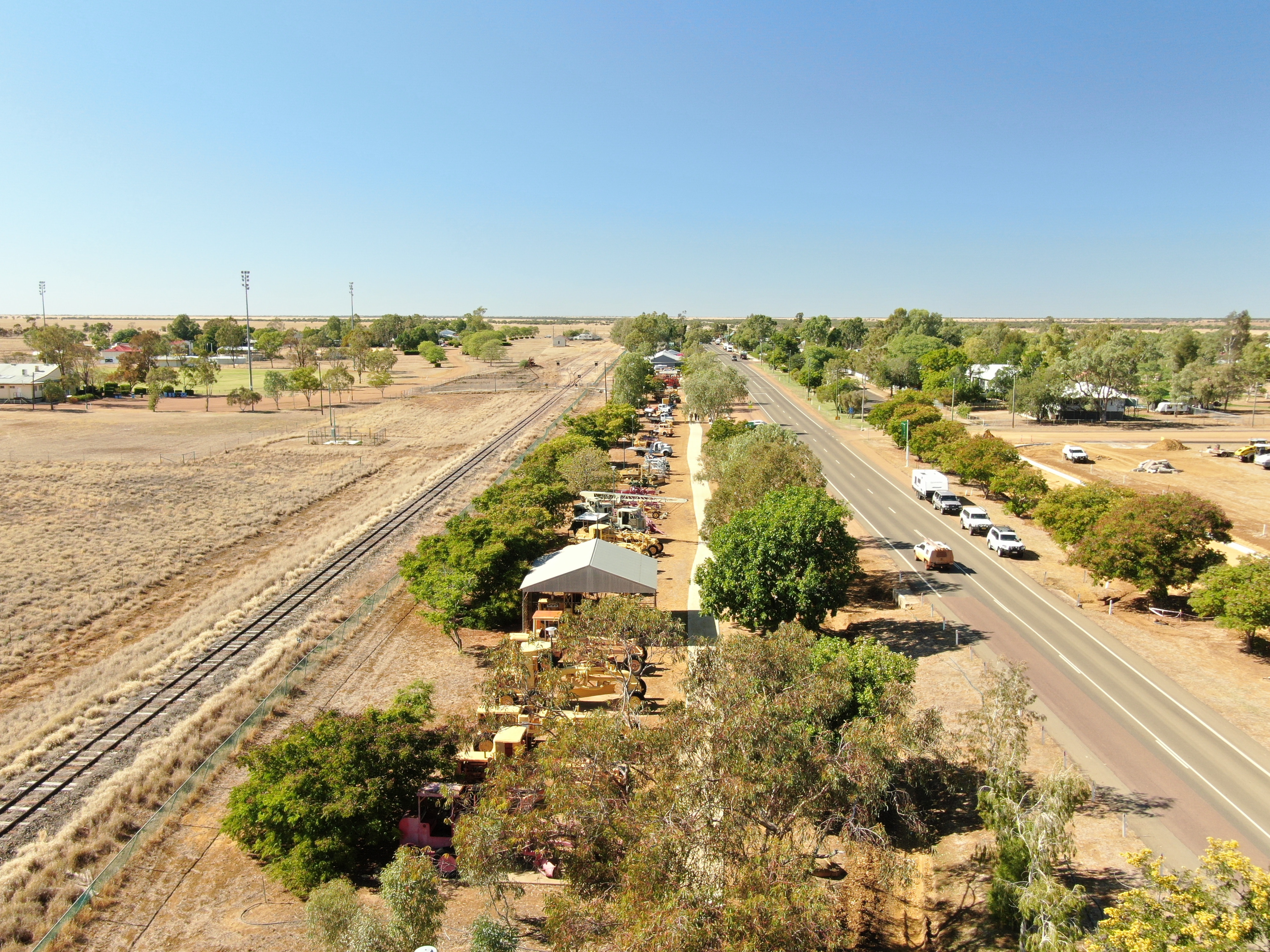 drone view of town, with line of trucks between a railway and road
