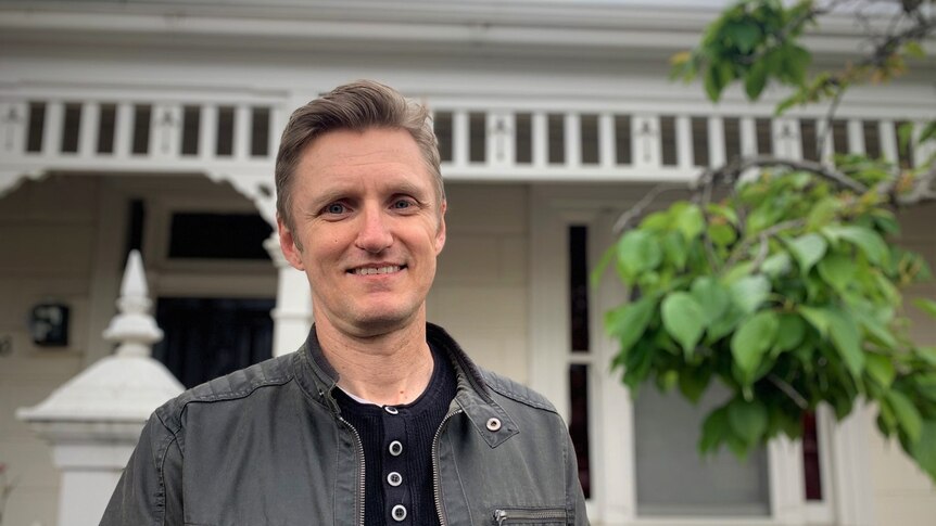 Brent Johnson smiling in front of his weatherboard home.