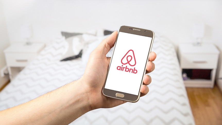 Airbnb app in a hand.