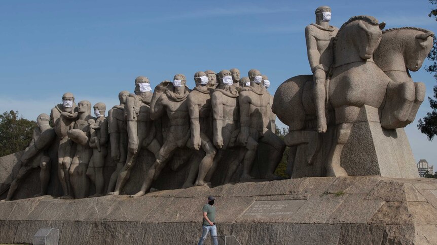 A row of concrete statues are all seen wearing face masks.