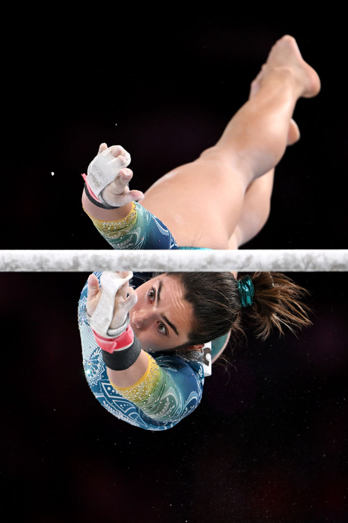 gymnast georgia godwin is captured flying through the air during an uneven bars routine reaching out for one of the bars