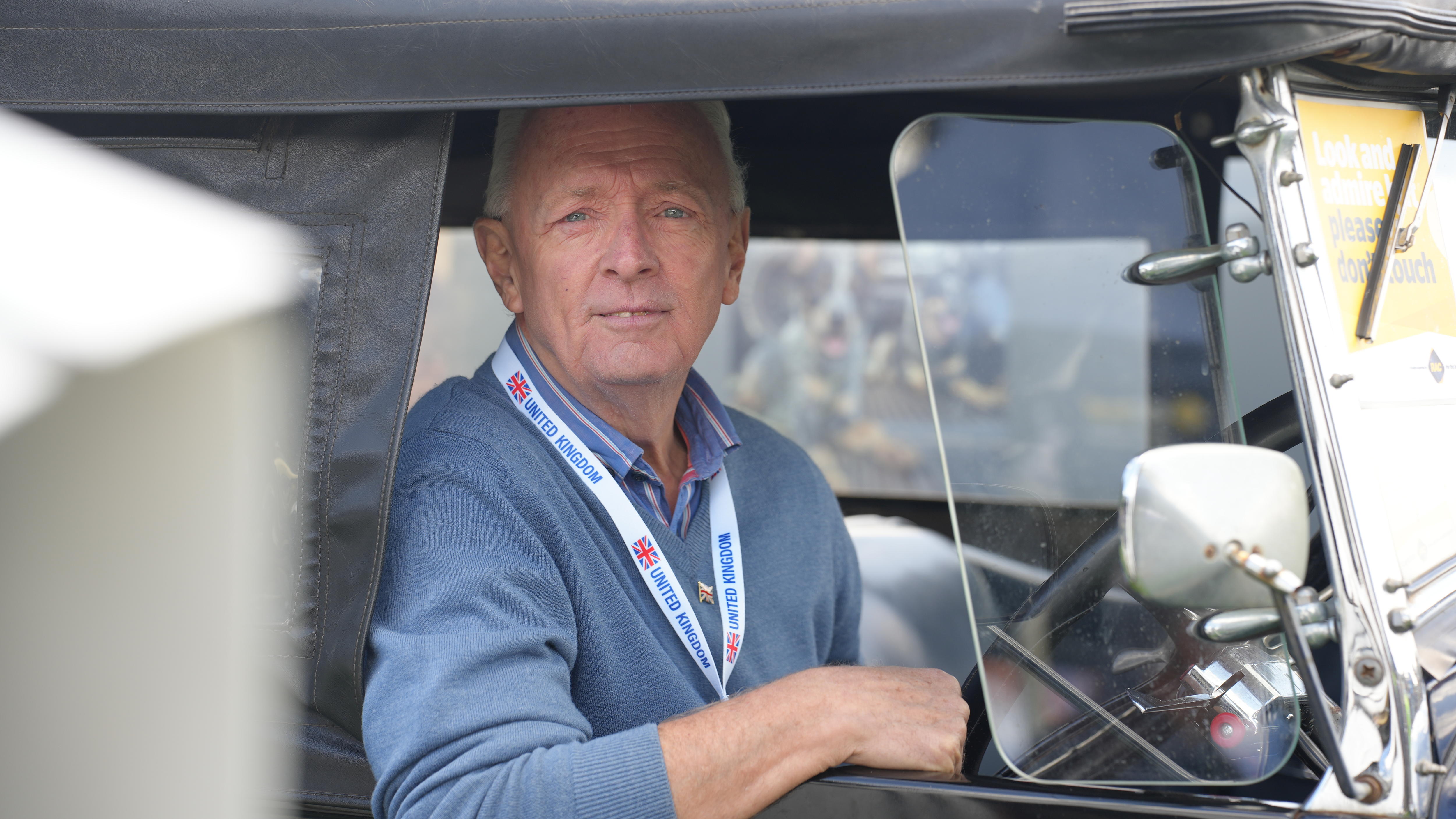 a man sitting in the front seat of his vintage car