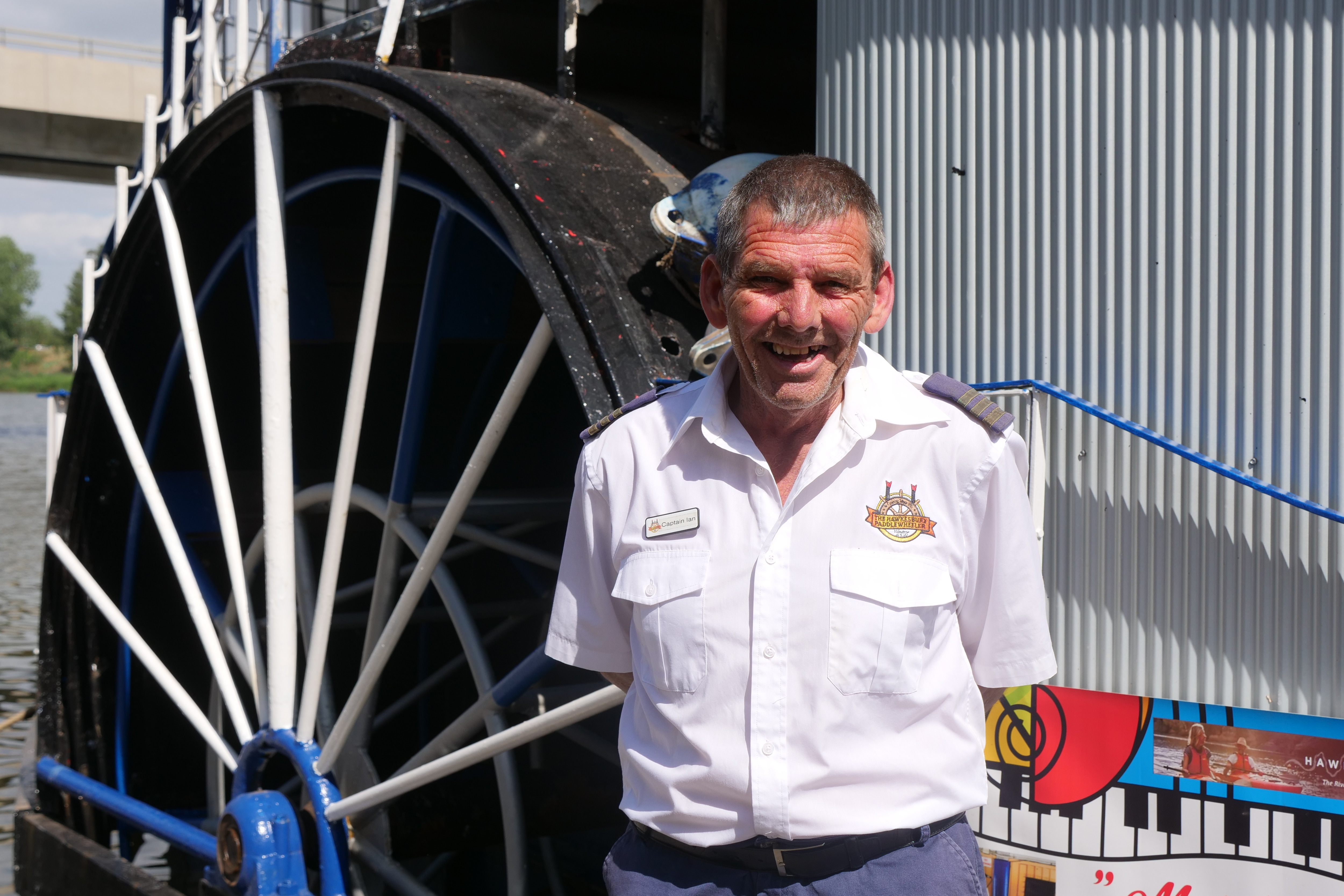 People gather on a paddle wheel boat docked on a river