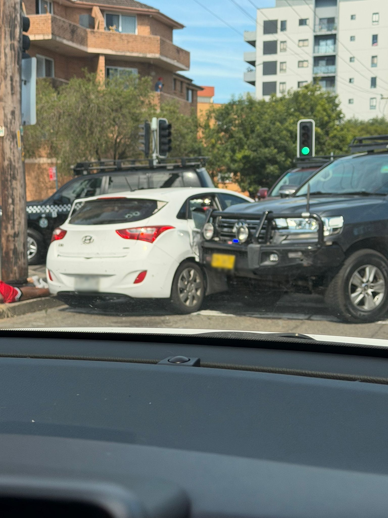 A police 4WD ramming a white car, windscreen shattered.