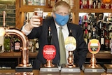 Boris Johnson, wearing a facemask, holds a pint of beer up.