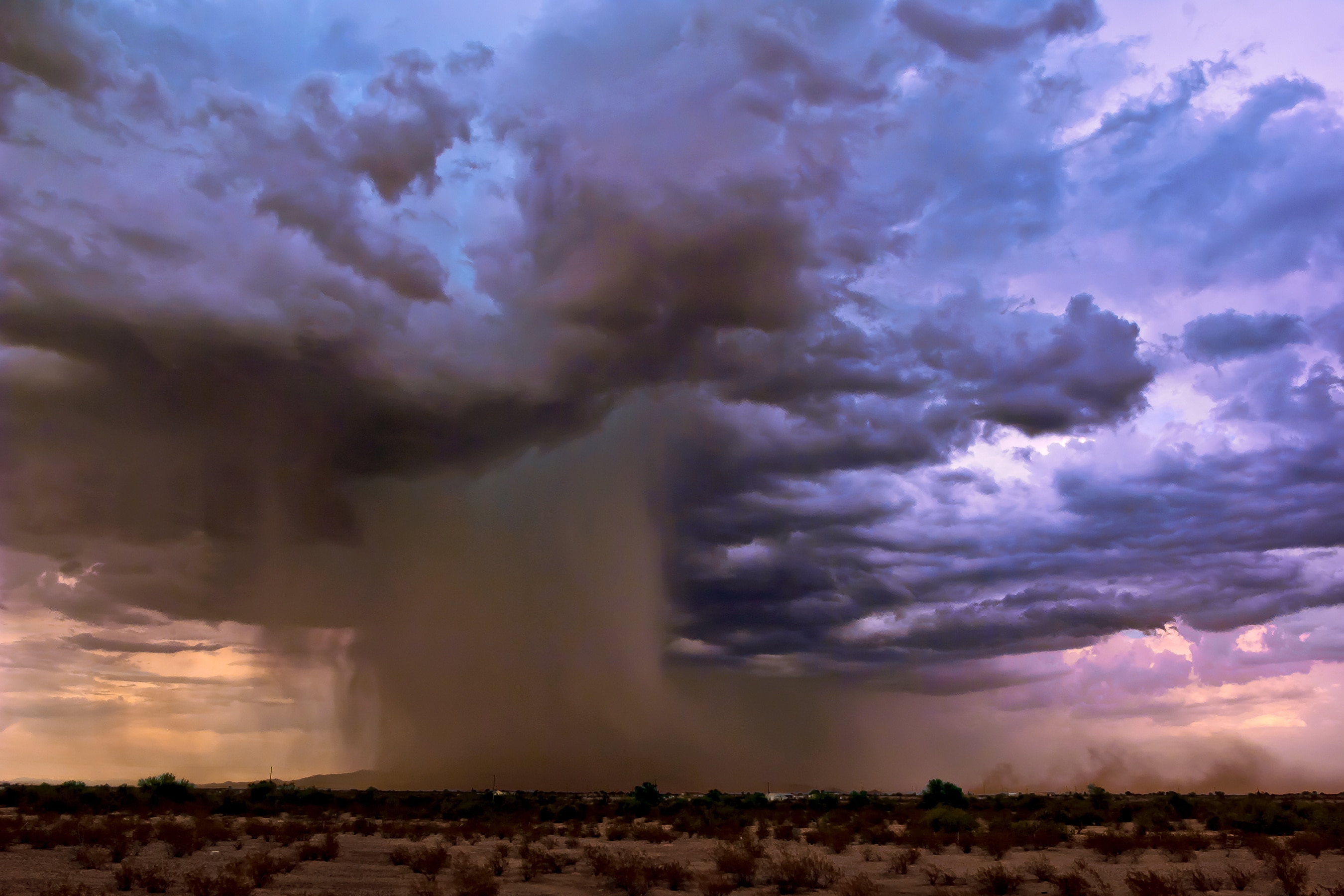 An image of dark clouds and intense rain falling on the landscape