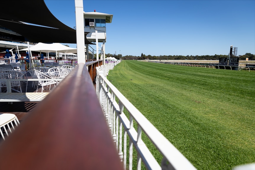 The home straight of a racecourse with the finishing post visible. 