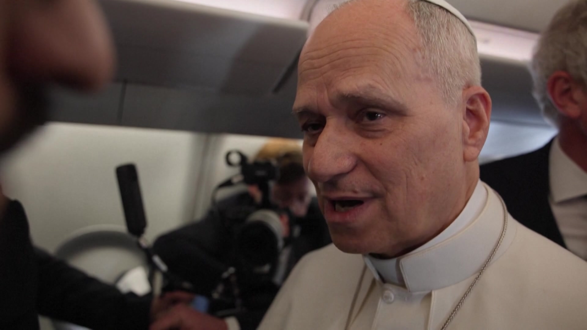 Pope Leo answers a reporter's question from aeroplane interior.