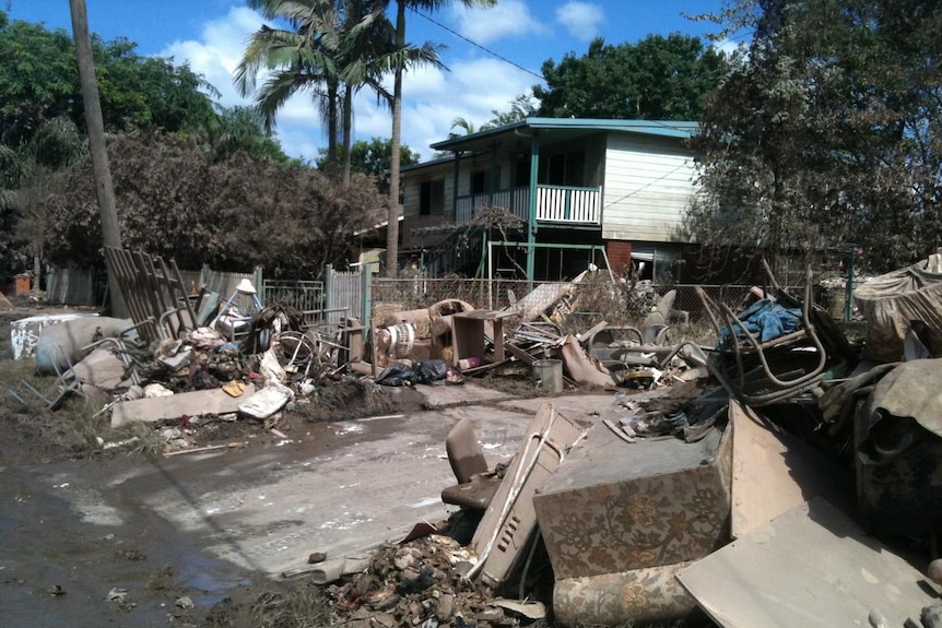 Household goods and debris scatter a flood-affected street in Goodna.
