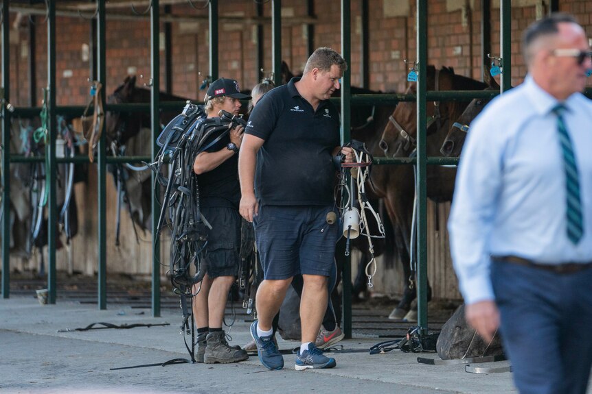 A man walks near stables.