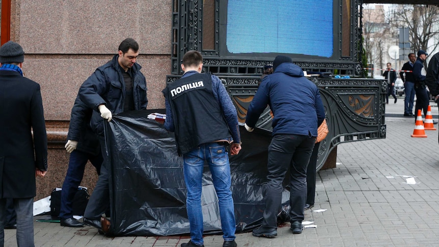 Forensic experts and police officers examine the scene following the killing of Denis Voronenkov in Kiev.