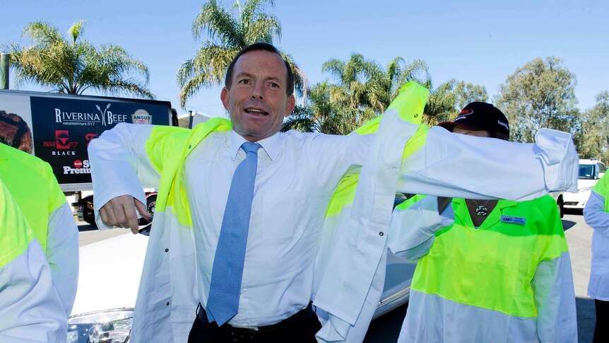 Tony Abbott pulls on a jacket