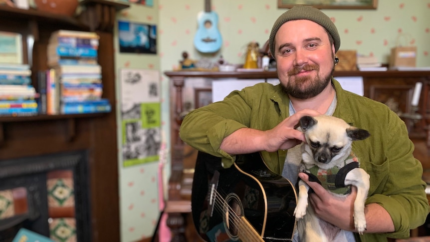 Harry poses in front of piano and bookshelf with dog