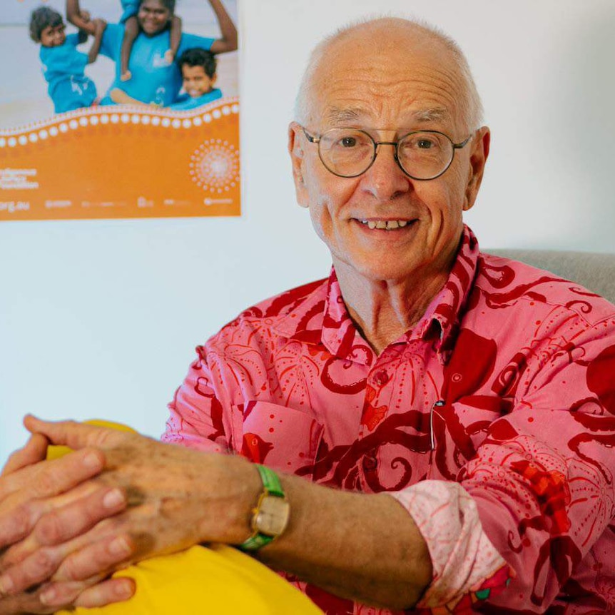 Dr Karl sitting in front of a poster for the Indigenous Literacy Foundation.