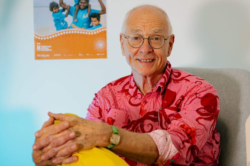 Dr Karl sitting in front of a poster for the Indigenous Literacy Foundation.