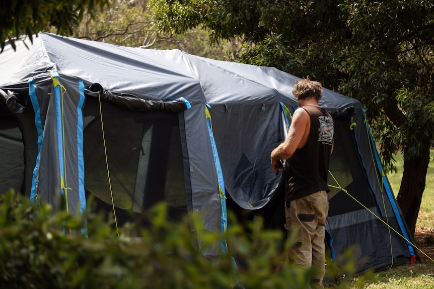 A man sets up a large tent.
