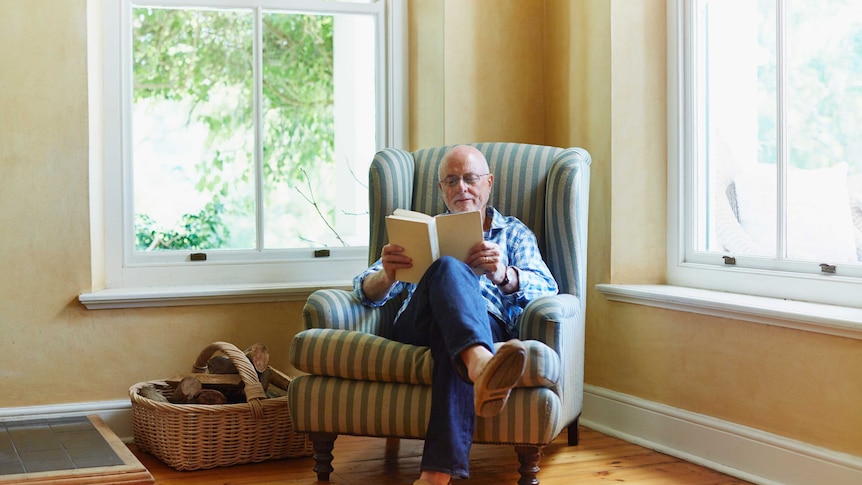 Man sitting in armchair reading a book