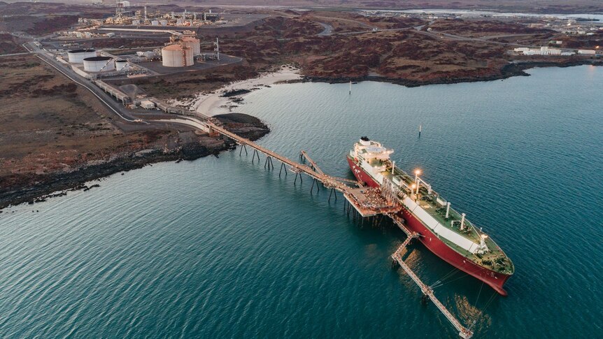Aerial picture of large LNG cargo ship loading at jetty off the red landscape of the Pilbara