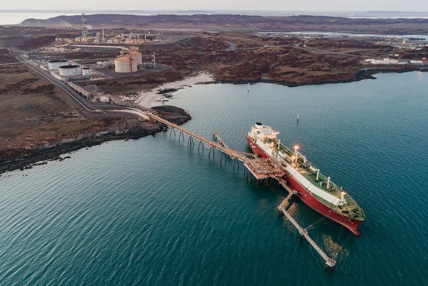 Aerial picture of large LNG cargo ship loading at jetty off the red landscape of the Pilbara