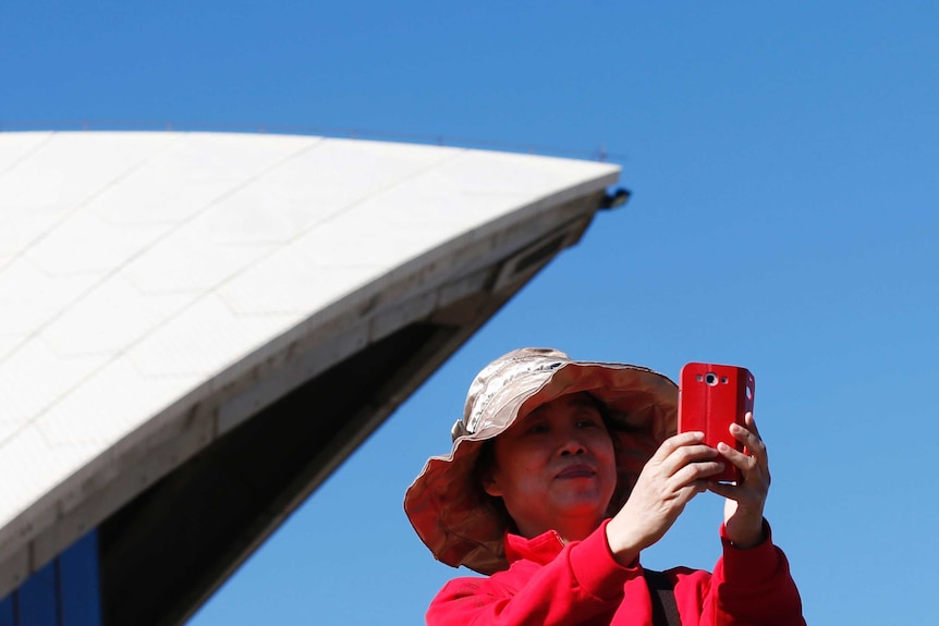 A Chinese tourist takes a picture from the steps of the Sydney Opera House