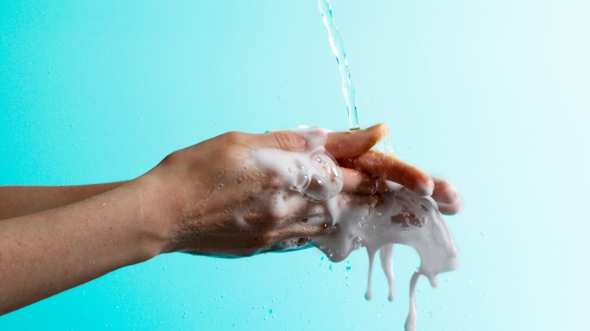 Soapy hands being rubbed together and rinsed with clean water.