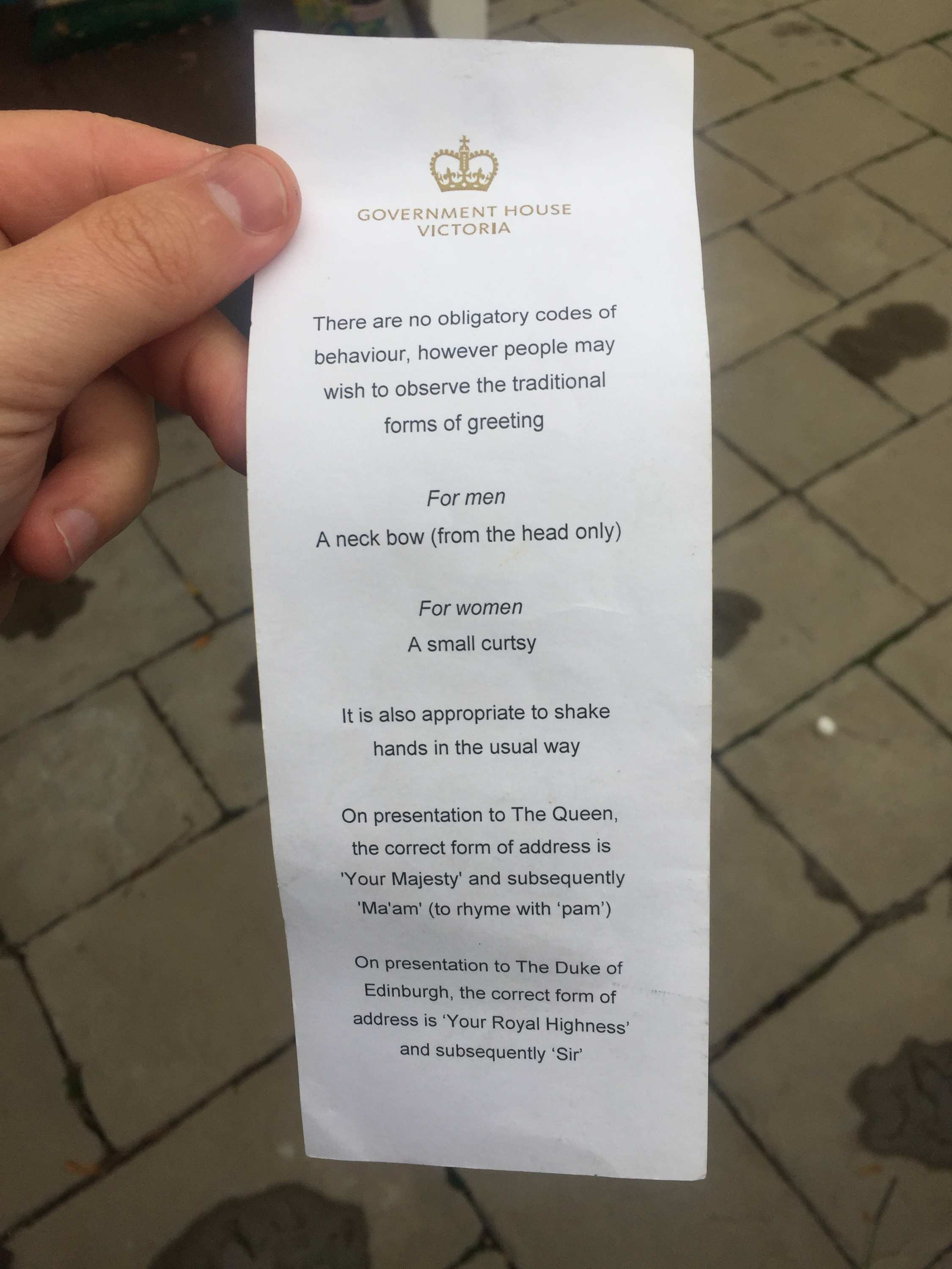 A hand holds a document explaining the protocol for addressing the Queen and Prince Philip.