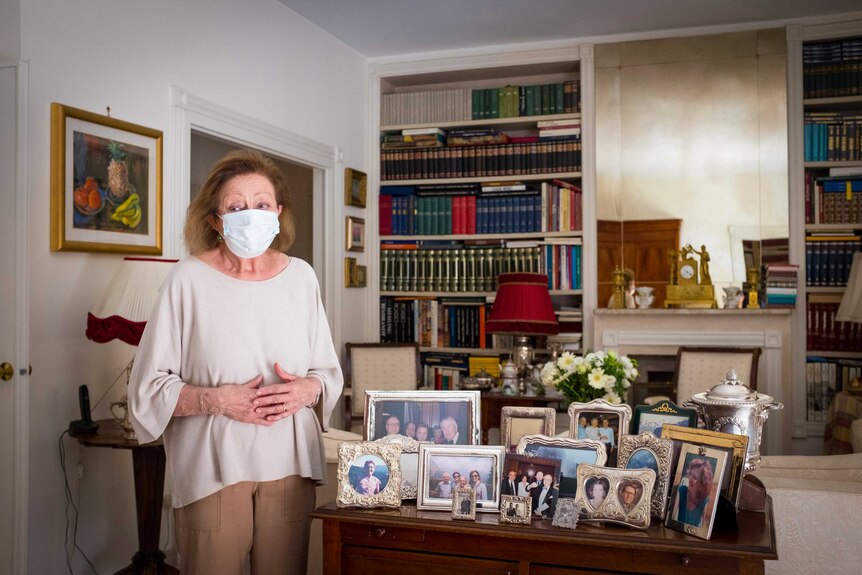 A woman in a face mask stands in a living room