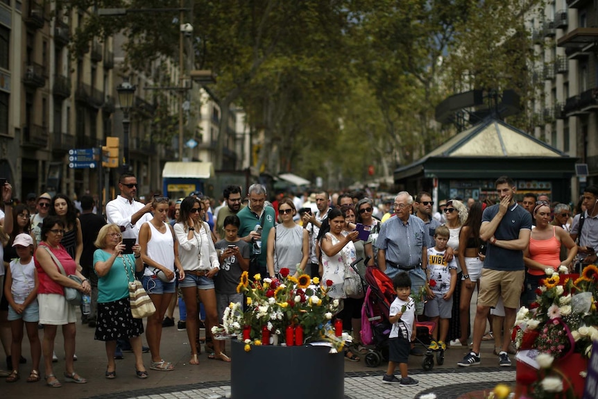 Barcelona citizens stand near a memorial