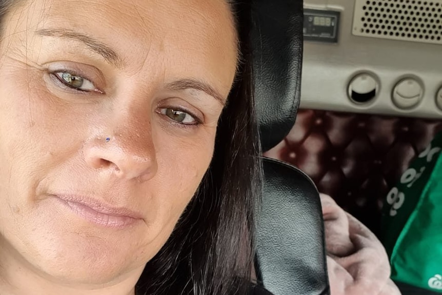 Brunette woman's selfie inside car, pursed lips.