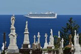 The Ruby Princess is seen in the background, a cemetery is seen in the foreground.