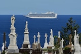 The Ruby Princess is seen in the background, a cemetery is seen in the foreground.