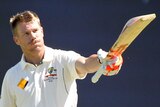 David Warner holds up his bat to celebrate a century.