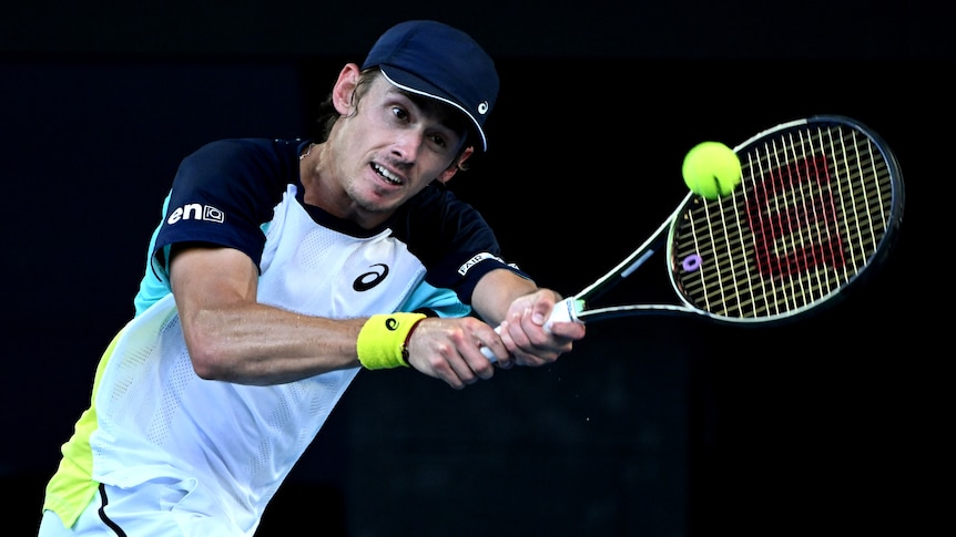 An Australian male tennis player hits a backhand return.