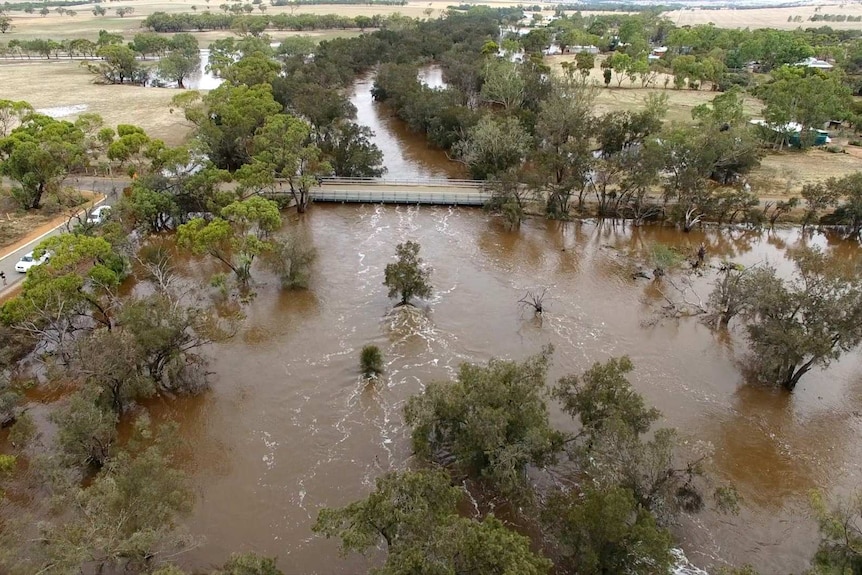 An aerial picture of an overflowing river in a rural area with a bridge just above the water level.