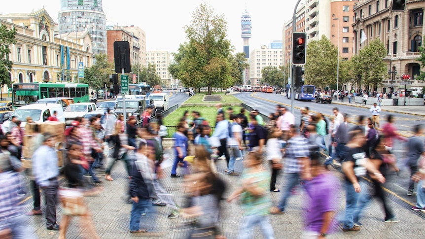 People cross a busy road in a blur of colour and movement
