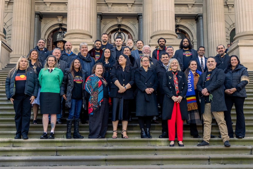 About two dozen First Nations people standing on the steps of Victorian Parliament