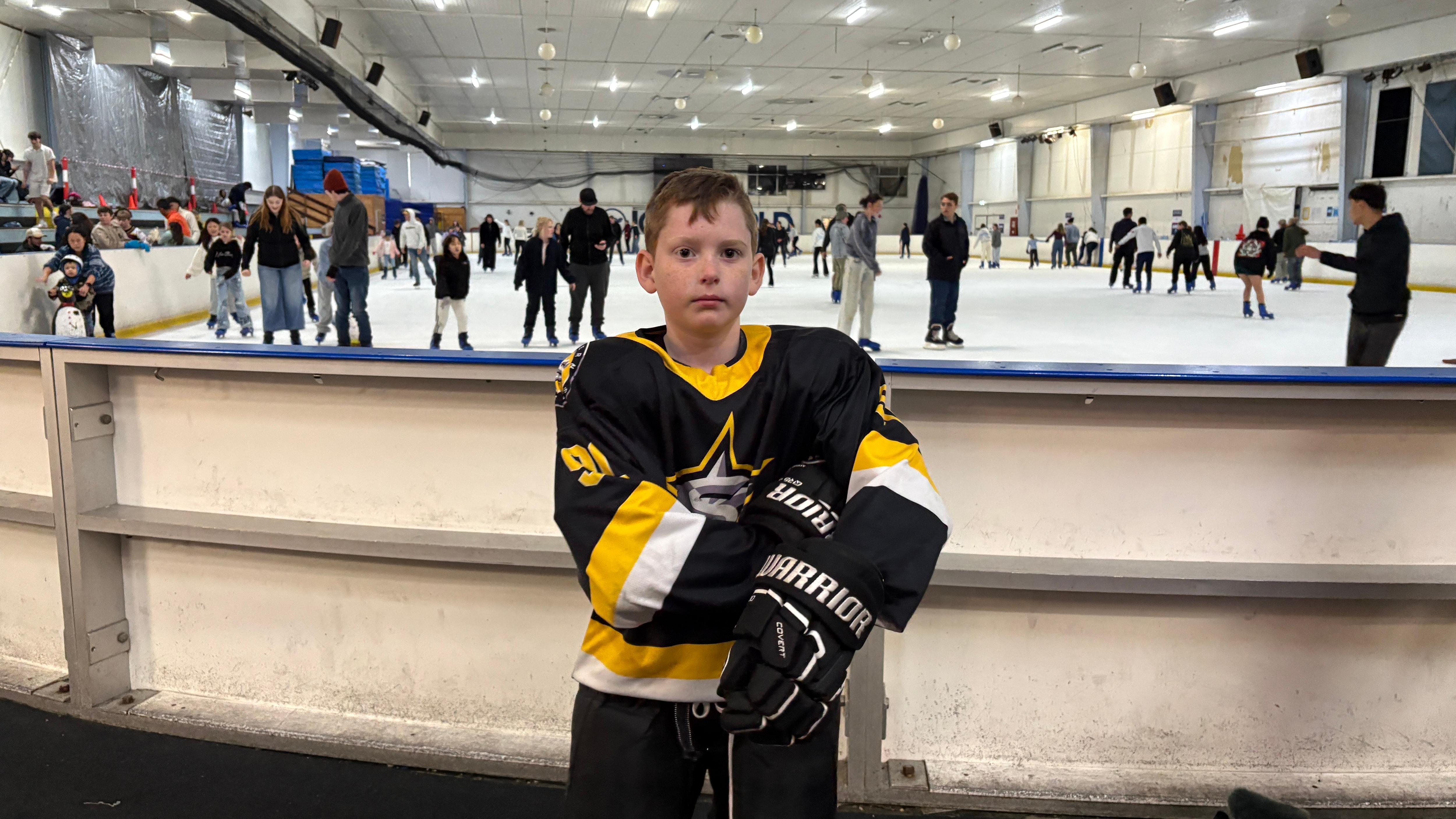 Nathaniel Coombes standing in front of an ice rink. 